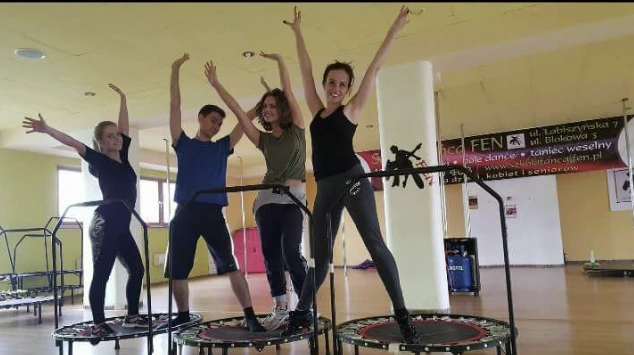 Uczestnicy zajęć fitness na trampolinach w sali treningowej